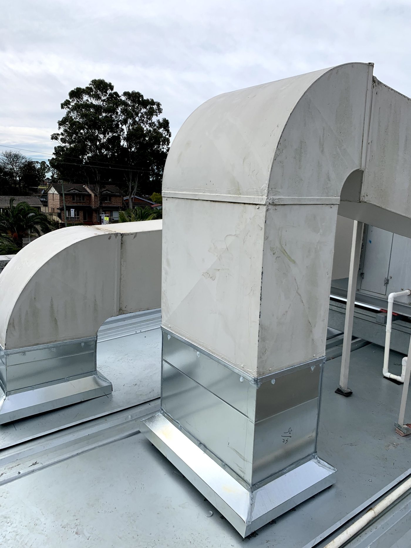 Curved sheet-metal ductwork risers on a commercial rooftop