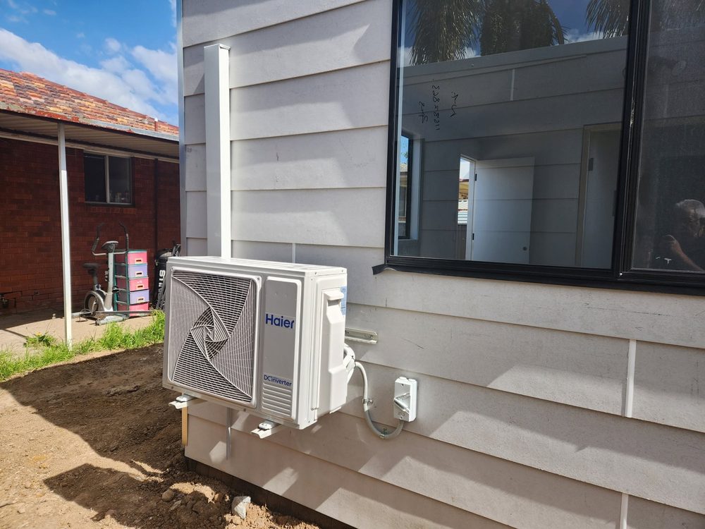 Outdoor condenser unit installed on the exterior wall of a house